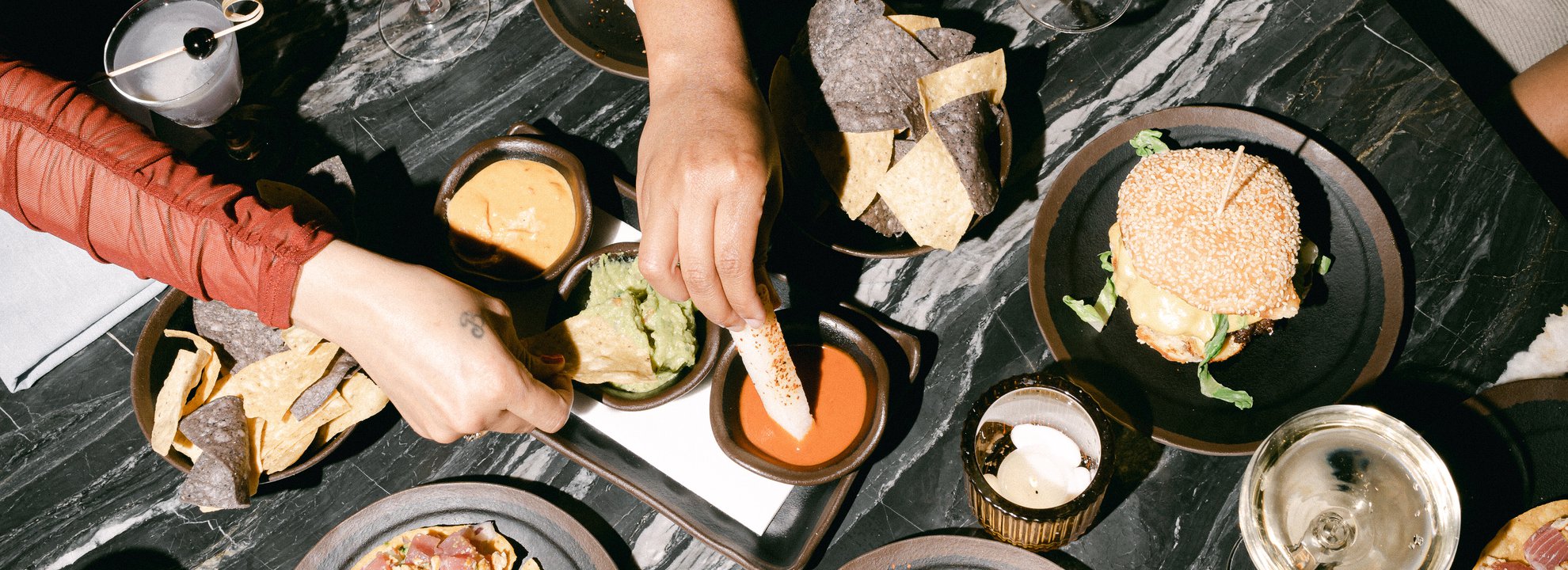 group of friends sharing a meal at selva chicago including burger, tacos and drinks located at the emily hotel fulton market west loop